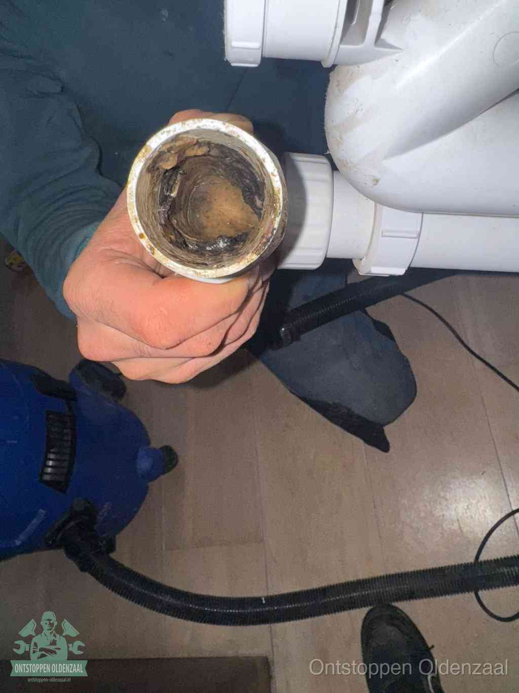 Een losgekoppeld PVC-afvoerbuisstuk dat van binnen volledig is dichtgeslibd met vet en vuil, de meest voorkomende oorzaak van verstoppingen in Oldenzaal