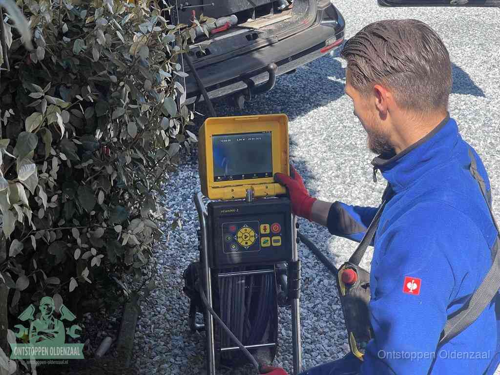 Een monteur bedient een rioolinspectiecamera met monitor en haspel om de verstopping in beeld te brengen in Oldenzaal
